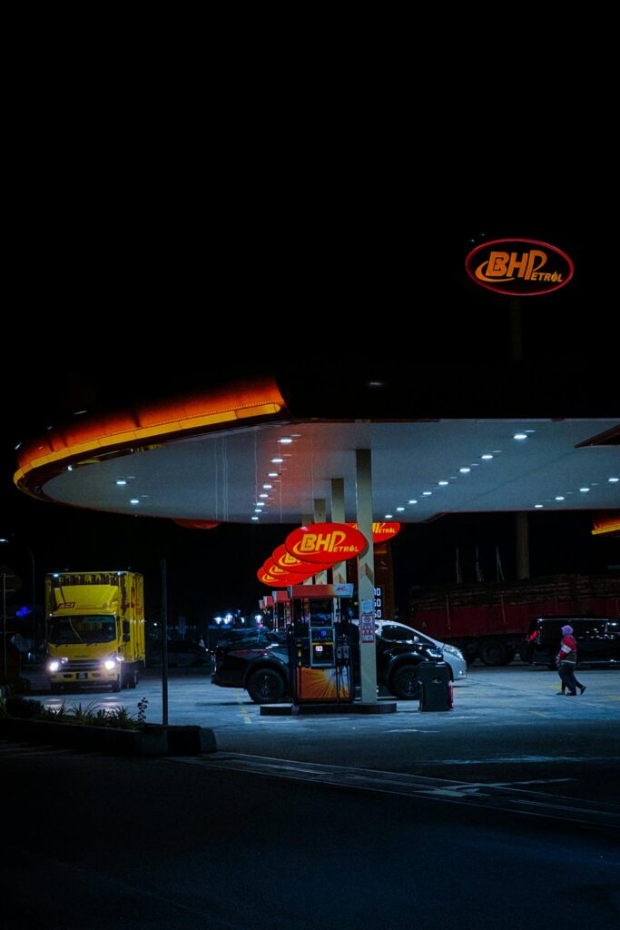 Illuminated BHPetrol station with vehicles at night in Sungkai, Malaysia.